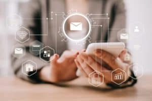 Cropped view of businesswoman using smartphone in office with email marketing icons
